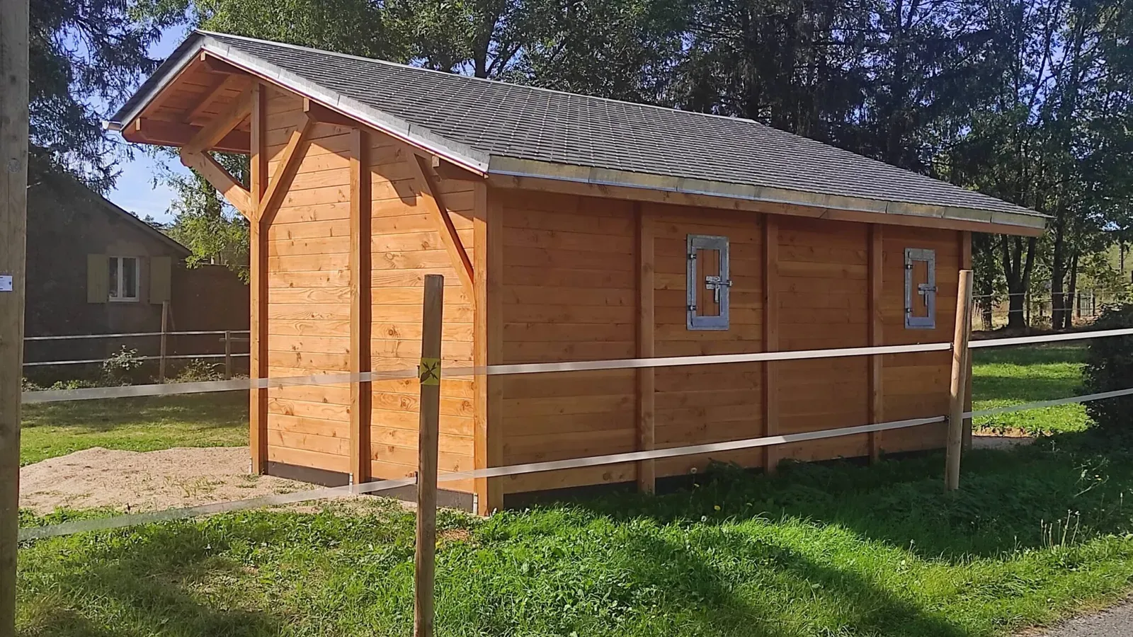 Abri de prairie en bois installé au bord d’un pré clôturé